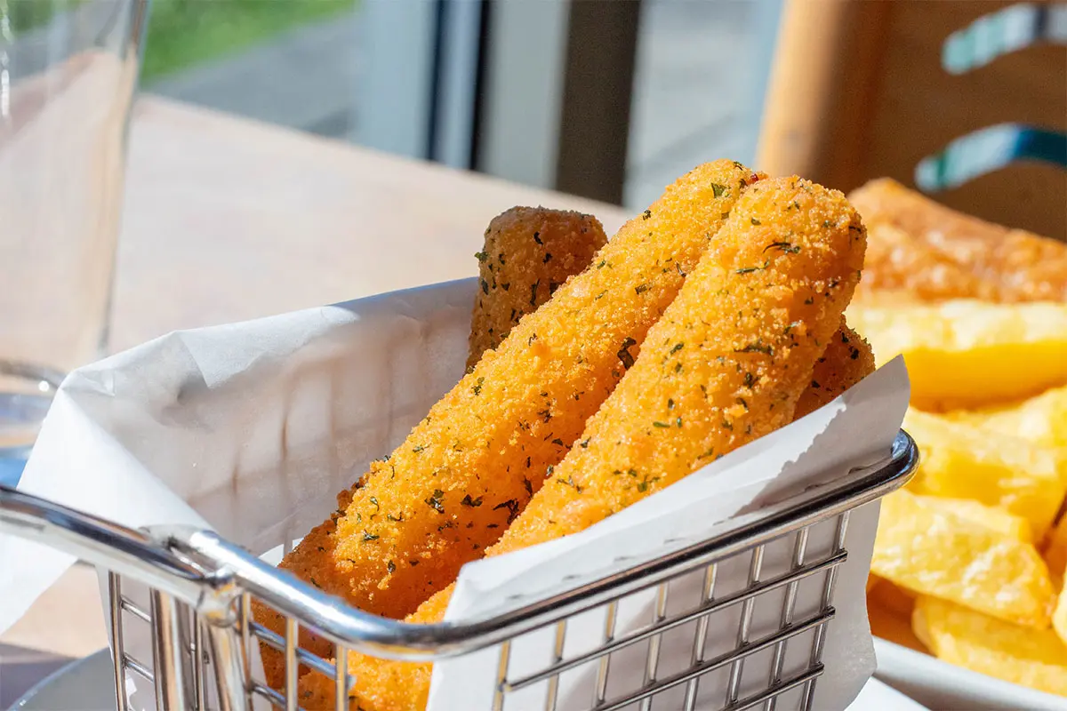 Close up photo of mozzarella sticks in a metal food basket