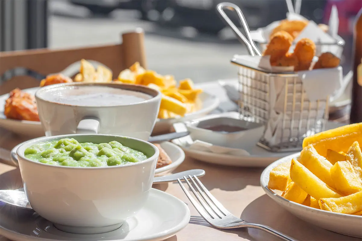 A bowl of mushy peas and other cuisine on a table