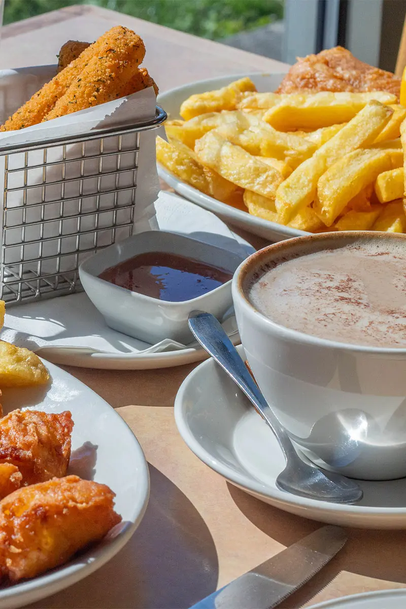Cup of coffee, plate of fish and chips and a basket of mozzarella sticks on the table in the Palmers Fish and Chips restaurant