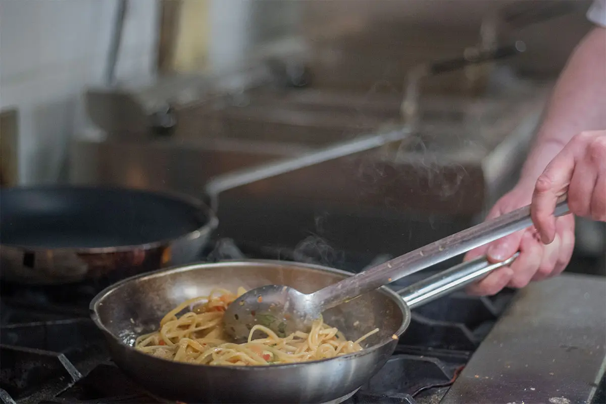 Chef cooking spaghetti in a sauce pan in the kitchen at The Royal Oak Over Stratton
