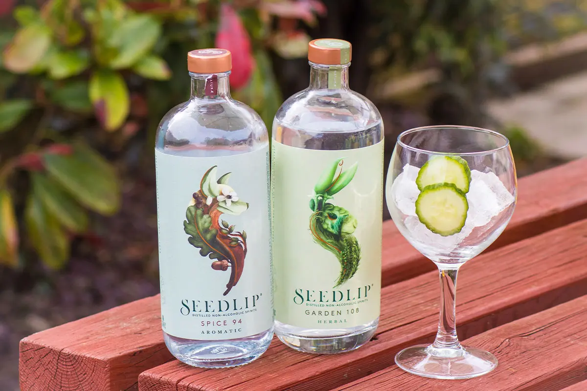 2 bottles of Seedlip distilled non-alcholic spirits next to a chilled glass with cucumbers in it