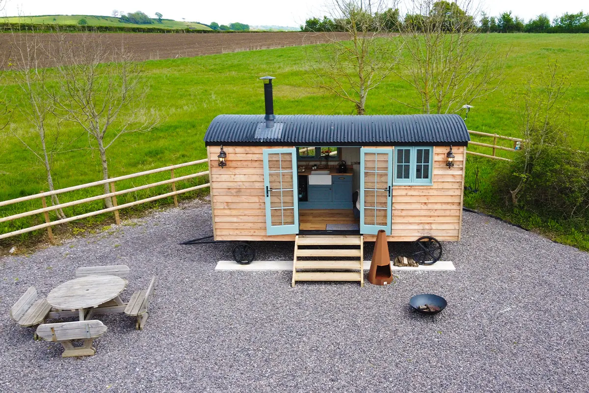 Aerial photograph of a shepherds hut on gravel, with grass in the background