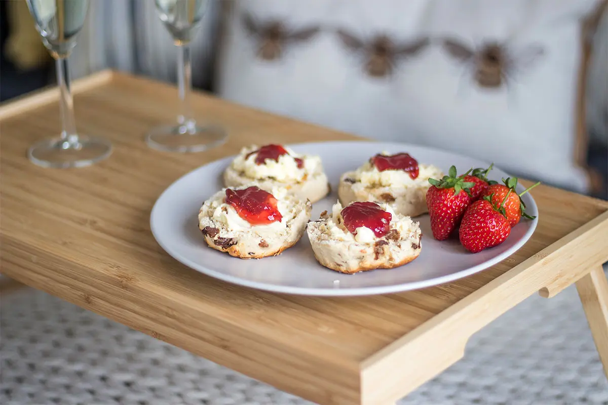 Scones with jam and cream on a plate with strawberries and champagne glasses