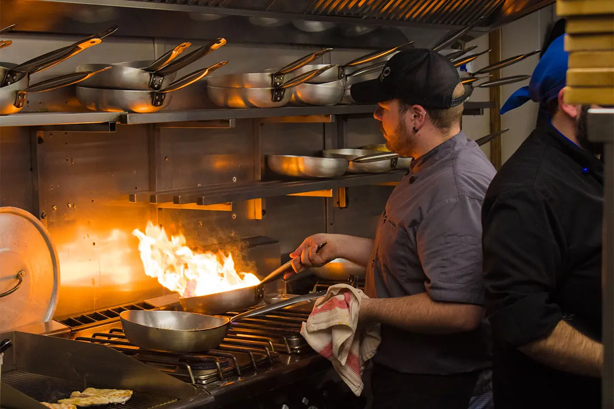 Tamburinos yeovil chef flambéing food in a frying pan with lots of lames