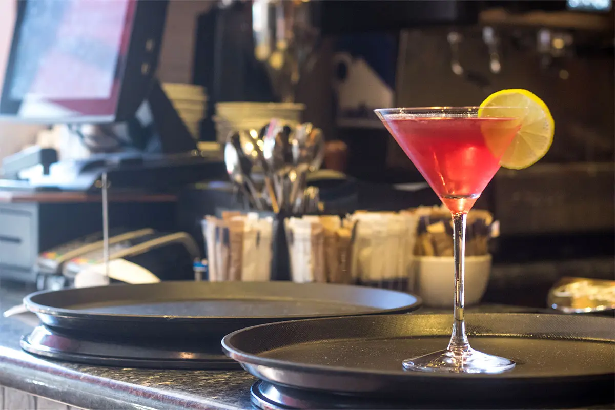 Red cocktail in a glass with a lemon on a tray at Tamburinos